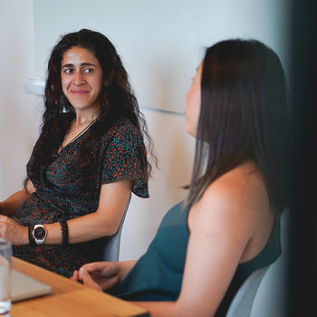 Marshmallow - An image of two female engineers in a meeting room. One engineer is smiling at the other. 