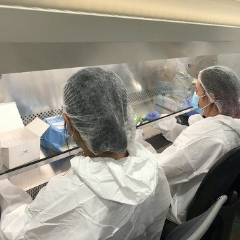 Uh-Oh Labs - Three team members in full PPE assembling product kits in the lab fume hood