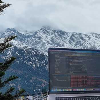 VMware - Laptop screen showing code with snow-capped mountains in the background
