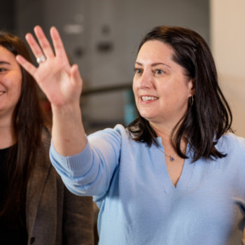 Audible - Woman pointing with whole hand while another woman looks on smiling